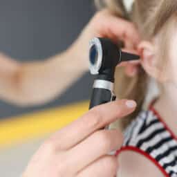 Doctor examining the ears of a young girl.