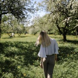 A young woman walking through a grassy park.